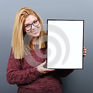 Portrait of smiling woman holding blank sign board.Studio portrait of young woman with sign card against gray background