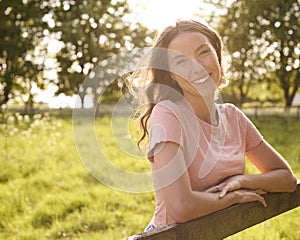 Portrait Of Smiling Woman Leaning On Fence On Walk In Countryside