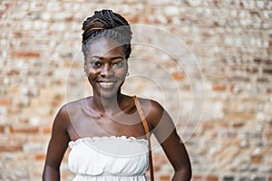 Portrait of smiling woman looking at camera against brick wall