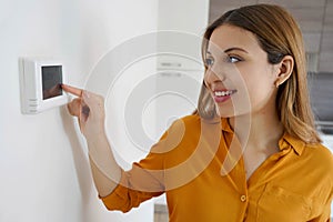 Portrait of smiling woman lowers the temperature on digital thermostat at home. Energy saving, efficient and smart technology