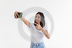 Portrait of a smiling woman making selfie photo on phone isolated on a white background
