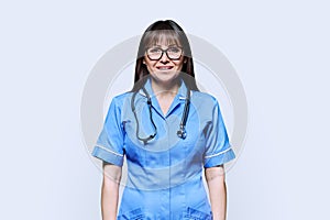 Portrait of smiling woman nurse in blue with stethoscope on white background