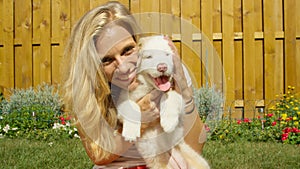 PORTRAIT: Smiling woman pets her cute fluffy white puppy while looking at camera