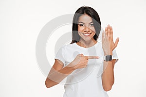 Portrait of a smiling woman pointing finger at smart watch