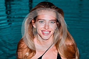 Portrait of smiling woman is posing near the swimming pool.