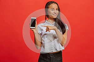 Portrait of a smiling woman in red dress showing blank smartphone screen