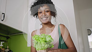 Portrait of a smiling woman with a salad in her hands in the kitchen at home. an erudite housewife holds greens and a