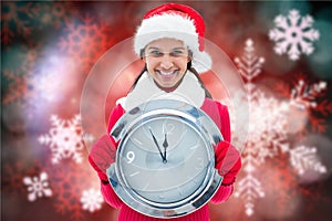 Portrait of smiling woman in santa hat holding clock against digitally generated background