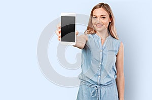 Portrait of a smiling woman showing blank smartphone screen isolated on a color background