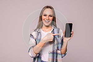 Portrait of a smiling woman showing blank smartphone screen on a white background