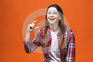 Portrait of smiling woman showing small amount of something, isolated against orange background