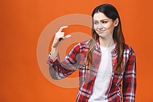 Portrait of smiling woman showing small amount of something, isolated against orange background