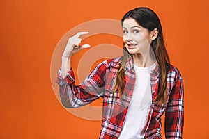 Portrait of smiling woman showing small amount of something, isolated against orange background