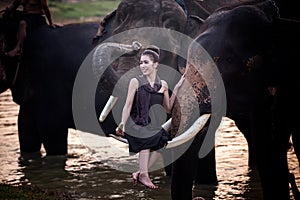 Portrait Of Smiling Woman Sitting on Elephant`s ivory In river, Thailand