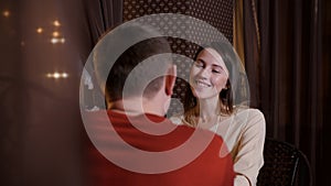 Portrait smiling woman sitting at table in cafe on romantic date with man. Happy woman laughing on evening rendezvous in