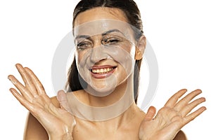 Portrait of a smiling woman with smeared makeup removing lotion on her face. in a white background