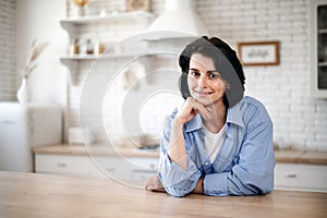 Portrait of smiling woman standing in kitchen, looking at camera