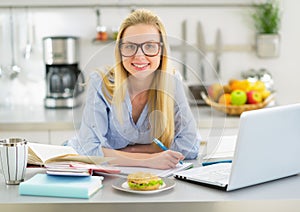 Portrait of smiling woman studying in kitchen