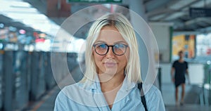 Portrait of smiling woman in subway metro. Happy satisfied glad pretty young milennial caucasian blonde woman in glasses