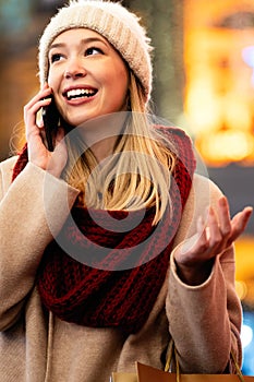 Portrait of smiling woman using mobile phone in the city at winter. People communication concept