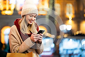 Portrait of smiling woman using mobile phone in the city at winter. People communication concept