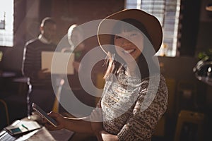 Portrait of smiling woman using smartphone against colleauges photo