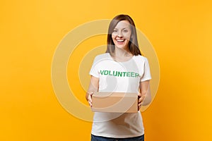 Portrait of smiling woman in white t-shirt with written inscription green title volunteer with blank cardboard box