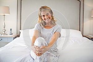 Portrait of smiling women sitting with legs crossed on bed