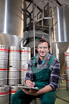 Portrait of smiling worker with clipboard sitting at warehouse