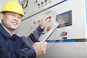 Portrait of smiling worker holding clipboard and checking controls in a gas plant, Beijing, China