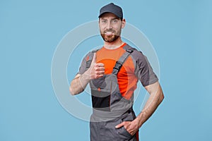 Portrait of smiling workerman In uniform showing thumbs up and looking at camera