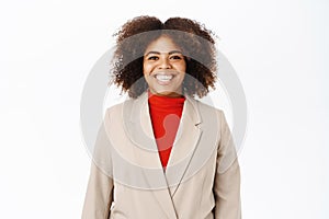 Portrait of smiling young african american saleswoman, looking professional and upbeat, standing over white background