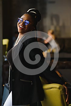 Portrait of a smiling young African American woman standing in front of her cafe with her arms crossed