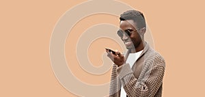 Portrait of smiling young african man holding smartphone using voice command recorder, assistant or takes calling, looking at