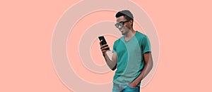 Portrait of smiling young african man with smartphone wearing t-shirt, sunglasses isolated on blue background