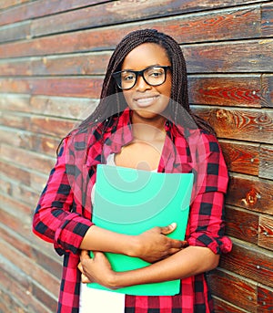 Portrait smiling young african woman in glasses holding folder over background