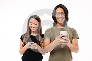 Portrait of a smiling young asian couple using mobile phones