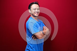 Portrait of smiling young asian man wearing black shirt isolated on red