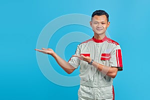 Portrait of smiling young Asian mechanic pointing to empty space isolated on blue background