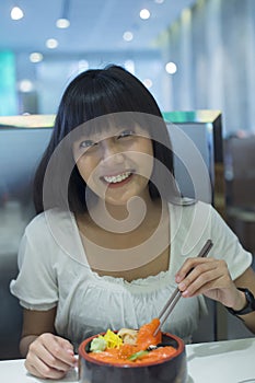 Portrait of smiling young asian woman eating japanese food