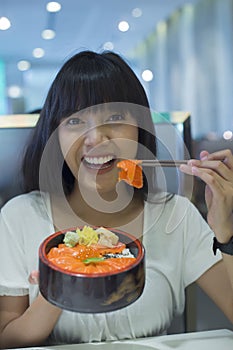 Portrait of smiling young asian woman eating japanese food