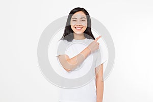 Portrait of smiling young asian woman wearing summer t shirt pointing at copy space by finger isolated on white template and blank