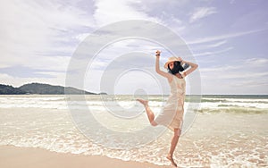 Portrait of smiling young beautiful woman jumping on the beach