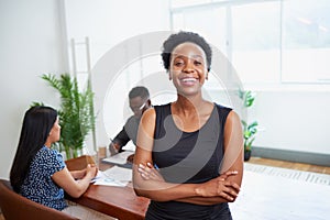 Portrait of a smiling young Black business woman arms folded in boardroom