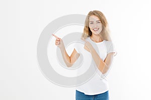 Portrait of smiling young blonde caucasian woman wearing summer t shirt pointing at copy space by finger isolated on white