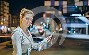 Portrait of smiling young blonde sportswoman listening music on mobile phone application