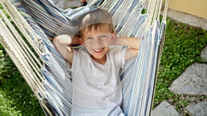 Portrait of smiling young boy sways and reclines in a garden hammock, capturing the spirit of summertime, the bliss of