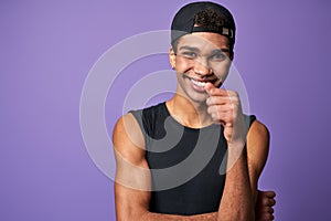 Portrait of smiling young brunette man in black t-shirt and cap. Happy latino model of trans gender