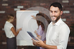 Portrait of smiling young businessman holding digital tablet