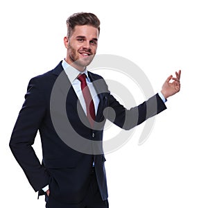Portrait of smiling young businessman presenting to side